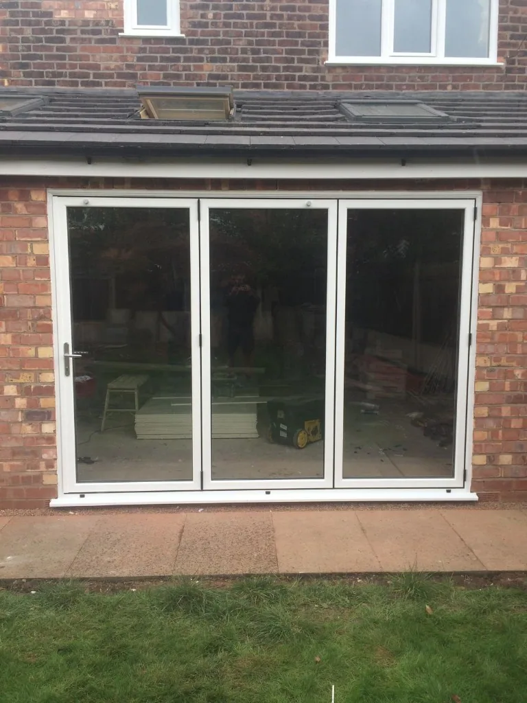 White three pane bi-fold doors on brick extension